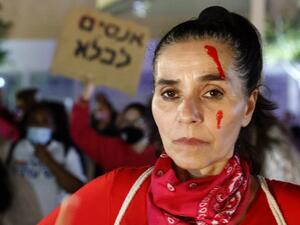 An Israeli woman with red paint on her face attends a protest in Tel Aviv against femicide, domestic violence, rape and murder cases against women in Israeli society, on February 8, 2021.  JACK GUEZ / AFP