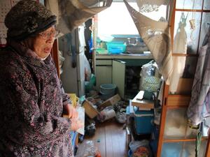 Japanese woman Taeko Naito stands next to her scattered kitchen at her home in Soma, Fukushima prefecture on February 14, 2021, after a 7.3-magnitude earthquake struck off Japan's east coast late on February 13. STR / JIJI PRESS / AFP