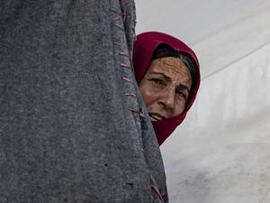 A woman looks on from behind a tent at the Kurdish-run al-Hol camp which holds suspected relatives of Islamic State (IS) group fighters, in the northeastern Syrian Hasakeh governorate, on February 17, 2021. Delil SOULEIMAN / AFP
