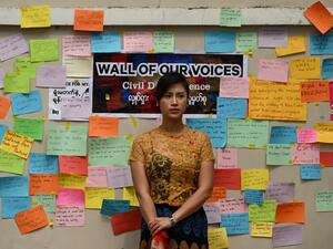 A woman stands in front of a wall with protest messages during a demonstration against the military coup in Yangon on February 18, 2021. Sai Aung Main / AFP