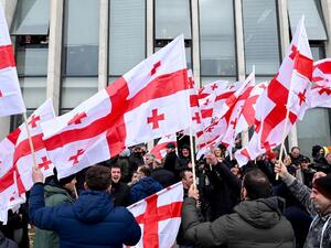 Georgian opposition supporters wave national flags reacting on the announcement of Prime Minister Giorgi Gakharia's resignation in front of the United National Movement (UNM) headquarters in Tbilisi on February 18, 2021. Vano Shlamov / AFP