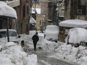 A man walks along a snow-covered street in the town of Bcharre in mount Lebanon, north of the capital Beirut, on February 19, 2021. JOSEPH EID / AFP