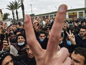 Policemen are seen on the sidelines as students chant slogans while demonstrating in the centre of Algeria's capital Algiers on February 23, 2021 a day after the second anniversary of the "Hirak" protest movement. The "Hirak" protest movement in April 2019 forced longtime president Abdelaziz Bouteflika into resigning. Police were deployed in force in Algiers, with security checkpoints and identity checks carried out around key flashpoints, while helicopters hovering overhead. RYAD KRAMDI / AFP