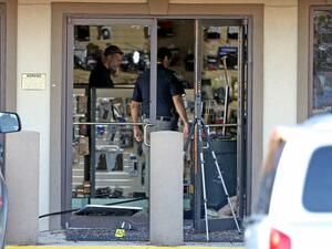 A body lies just inside the shattered front door at the Jefferson Gun Outlet as investigators work the scene on February 20, 2021 in Metairie, Louisiana. According to reports, three people were killed and two injured after an altercation lead to gunfire at an indoor shooting range. Michael DeMocker/Getty Images/AFP