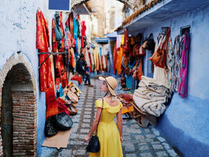 Colorful traveling by Morocco. Young woman in yellow dress walking in medina of blue city Chefchaouen  (Shutterstock)