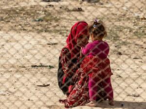 A young girl interacts with a toddler at the Kurdish-run al-Hol camp 