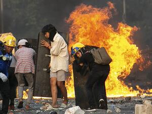 Protesters take cover behind homemade shields as they confront the police during a crackdown on demonstrations against the military coup in Yangon 