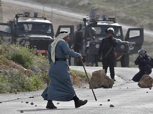 An elderly Palestinian man walks amidst clashes between demonstrators and Israeli security forces in the village of Beita, south of Nablus, after Israeli settlers announced that they would visit a historic site in the village 