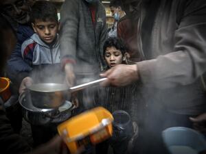 A boy waits as Palestinian Walid al-Hattab (R) distributes soup to people in need during the Muslim fasting month of Ramadan in Gaza City on April 14, 2021, amid the COVID-19 pandemic