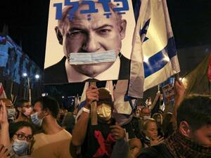 Israeli protesters hold a poster depicting their Prime Minister Benjamin Netanyahu gagged by a surgical protection mask in front of Netanyahu's residence, Jerusalem, Sept. 12, 2020. (AFP) Israeli protesters hold a poster of PM Netanyahu gagged by a surgical protection mask