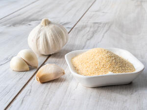 Bowl with granulated dried garlic on wooden table