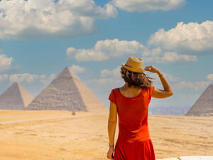 A young tourist in a red dress looking at the Pyramids of Giza