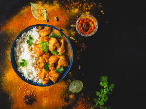 Utter chicken with basmati rice in bowl, spices, black background