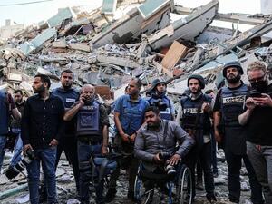 يقفون على حطام مكاتبهم , بعدما قصفت طائرات الاحتلال البرج الذي يتواجد فيه مكاتب الصحافة المحلية والدولية .