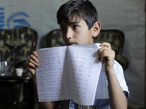 Eleven-year-old Syrian refugee Mohammad shows his Arabic writing notebook inside his family's tent at a refugee camp in the area of Tebrol in Lebanon's eastern Bekaa valley 