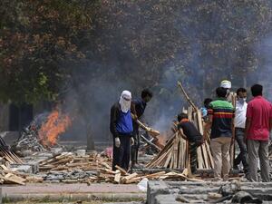 Relatives stand near burning pyres of people who died of the Covid-19 