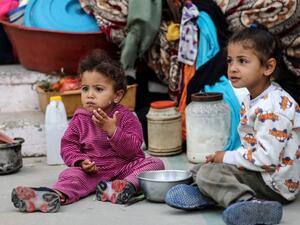 Palestinan children eat as families took shelter at a United Nations (UN) school in Rafah in the southern Gaza Strip on May 17, 2021. Israeli air strikes hammered the Hamas-controlled territory after a week of violence which has killed more than 200 people, the large majority Palestinian, despite international calls for de-escalation