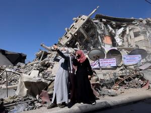 Palestinian women pose for a 'selfie' picture in front of a demolished building in the Al-Remal commercial district in Gaza City, recently targeted by Israeli air strikes, on May 23, 2021. Gazans started piecing back their lives after a devastating conflict with Israel that killed more than 200 people and made thousands homeless in the impoverished Palestinian enclave, days after an Egypt-brokered ceasefire ended deadly Israeli air strikes and rocket fire out of it towards Israel