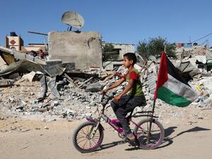 A Palestinian child rides his bicycle in front of the ruins of a building destroyed during recent Israeli bombing in Rafah, in the southern Gaza Strip, on May 26, 2021. Diplomatic efforts are underway to solidify a fragile Egypt-brokered truce that halted the fighting, with plans to rebuild the Gaza Strip where Israeli air strikes damaged infrastructure and levelled buildings