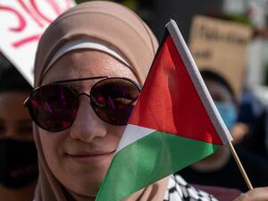 A woman holds the flag of Palestine next to her face during a pro-Palestine protest 
