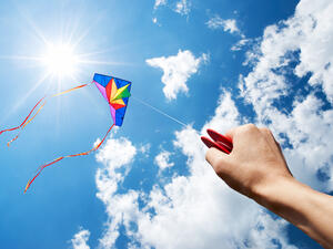 Kite flying in a beautiful sky with sun and clouds