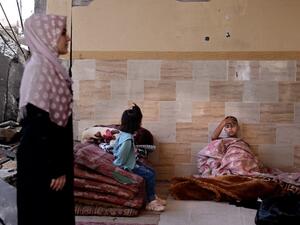 A sick child rests as other members of the Abu Ghadyan Palestinian family gather some belongings, before moving to a school run by the United Nations Relief and Works Agency for Palestine Refugees (UNRWA) where they will be living temporarily