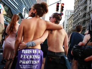 Topless attendees hold each other during the annual Dyke March
