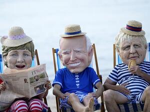Climate activists wearing giant heads depicting the leaders of the G-7