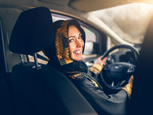 Beautiful arabian woman driving a car looking at camera.