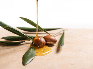 Argan oil, used for cosmetics, pouring over two argan seeds on a stone table.
