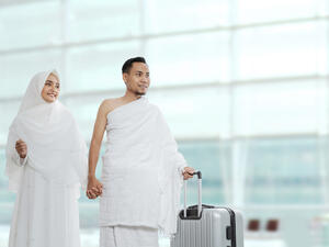 Muslim couples wife and husband wearing white traditional clothes for Ihram ready for Hajj walk in the airport