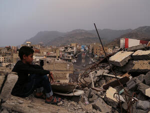 A child from Taiz City sits on the ruins of his ruined home because of the war on city-Yemen.