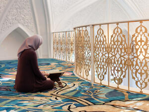 A young Muslim woman reads the Quran in the beautiful mosque