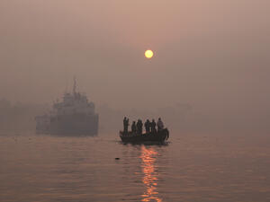 A landscape view of the brahmaputra river national park of the Sundarbans mangrove forest, one of the largest such forests in the world in a foggy day with a small boat full of people