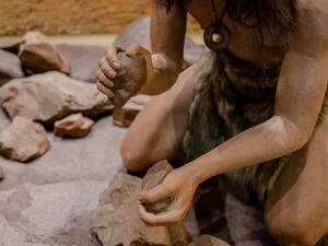 man set on fire with fire stone for cooking in stone age