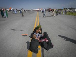 Several Afghans sit on the tarmac awaiting to leave from Kabul's airport on August 16, 2021. © 2021 WAKIL KOHSAR/AFP via Getty Images European States Should Set Example on Asylum, Resettlement-HRW