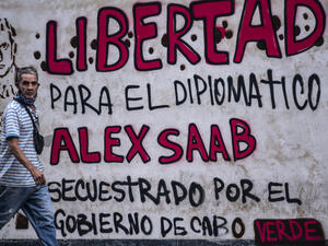 In this file photo taken on February 23, 2021 A man walks past a graffiti reading "Freedom for diplomat Alex Saab, kidnapped by the government of Cape Verde" in Caracas. (Photo by Yuri CORTEZ / AFP) / NO USE AFTER OCTOBER 8, 2021  The extradition by Cape Verde is a political move sacrificing its constitution.