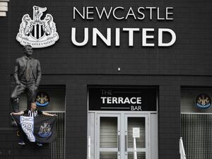 A Newcastle United supporter is seen posing in front of the statue of the late former manager Bobby Robson outside the club's stadium St James' Park in Newcastle upon Tyne in northeast England on October 8, 2021, after the sale of the football club to a Saudi-led consortium was confirmed the previous day. (Photo by Oli SCARFF / AFP)