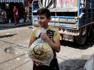 A young boy leaves a bakery with a bag of bread in a Beirut Suburb 