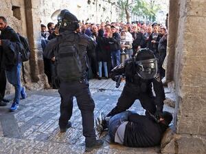Israeli forces immobilize a Palestinian man at an entrance to the al-Aqsa