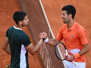 Spain's Carlos Alcaraz (L) and Serbia's Novak Djokovic shake hands at the end of their 2022 ATP Tour Madrid Open tennis tournament men's singles semi-final match at the Caja Magica in Madrid on May 7, 2022. (Photo by GABRIEL BOUYS / AFP)