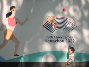 A child plays in front of a wall with images of the 2022 Asian Games in Hangzhou, in China's eastern Zhejiang province on May 8, 2022. China's ambitions to be a global sporting hub took a heavy blow as the May 6, 2022 postponement of this year's Asian Games further isolated a country already cut off by its hardline zero-Covid strategy. (Photo by AFP) / CHINA OUT