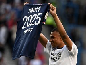 Paris Saint-Germain's French forward Kylian Mbappe poses with a jersey after the announcement he staying at PSG until 2025 before the French L1 football match between Paris Saint-Germain (PSG) and Metz at the Parc des Princes stadium in Paris on May 21, 2022. (Photo by Anne-Christine POUJOULAT / AFP)