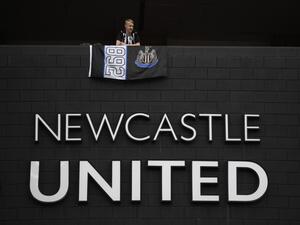 A Newcastle United football club supporter stands with a flag above the club logo at their stadium St James' Park in Newcastle upon Tyne in northeast England on October 8, 2021. (Photo by Oli SCARFF / AFP)