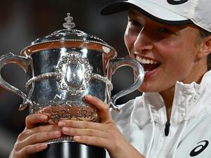 Poland's Iga Swiatek poses with the trophy after winning against US' Coco Gauff at the end of their women's single final match on day fourteen of the Roland-Garros Open tennis tournament at the Court Philippe-Chatrier in Paris on June 4, 2022. Iga Swiatek cruised to her second French Open title by dominating teenager Coco Gauff in the final as the world number one claimed her 35th successive victory. (Photo by Anne-Christine POUJOULAT / AFP)
