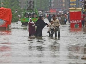 People wade across a flooded street in Karachi 