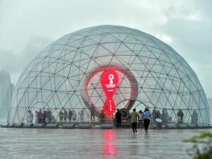 People take cover inside the FIFA World Cup Qatar 2022 countdown clock during heavy rains in the Qatari capital Doha on July 28, 2022. (Photo by AFP)
