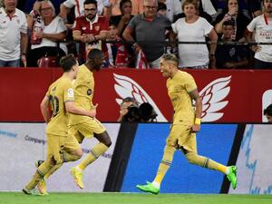 Barcelona's Brazilian forward Raphinha (R) celebrates with teammates after scoring his team's first goal during the Spanish league football match between Sevilla FC and FC Barcelona at the Ramon Sanchez Pizjuan stadium in Seville, on September 2, 2022. (Photo by CRISTINA QUICLER / AFP)