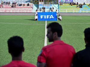 Youths hold a banner with the FIFA emblem before the start of a football match between Shaheen Asmayee and the Abasin Sape during the Amn Tournament, which includes six Afghan Premier League clubs, at Afghanistan Football Federation Stadium in Kabul on November 5, 2021. (Photo by Hector RETAMAL / AFP)