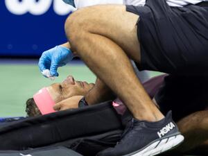 Spain's Rafael Nadal lies on the court and receives medical attention after hitting himself in the face with his racket during his 2022 US Open Tennis tournament men's singles second round match against Italy's Fabio Fognini at the USTA Billie Jean King National Tennis Center in New York, on September 1, 2022. (Photo by COREY SIPKIN / AFP)